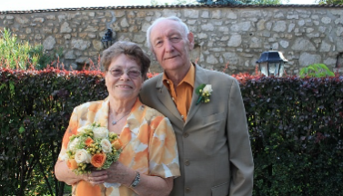 Photo of an elderly couple in front of a stonewall